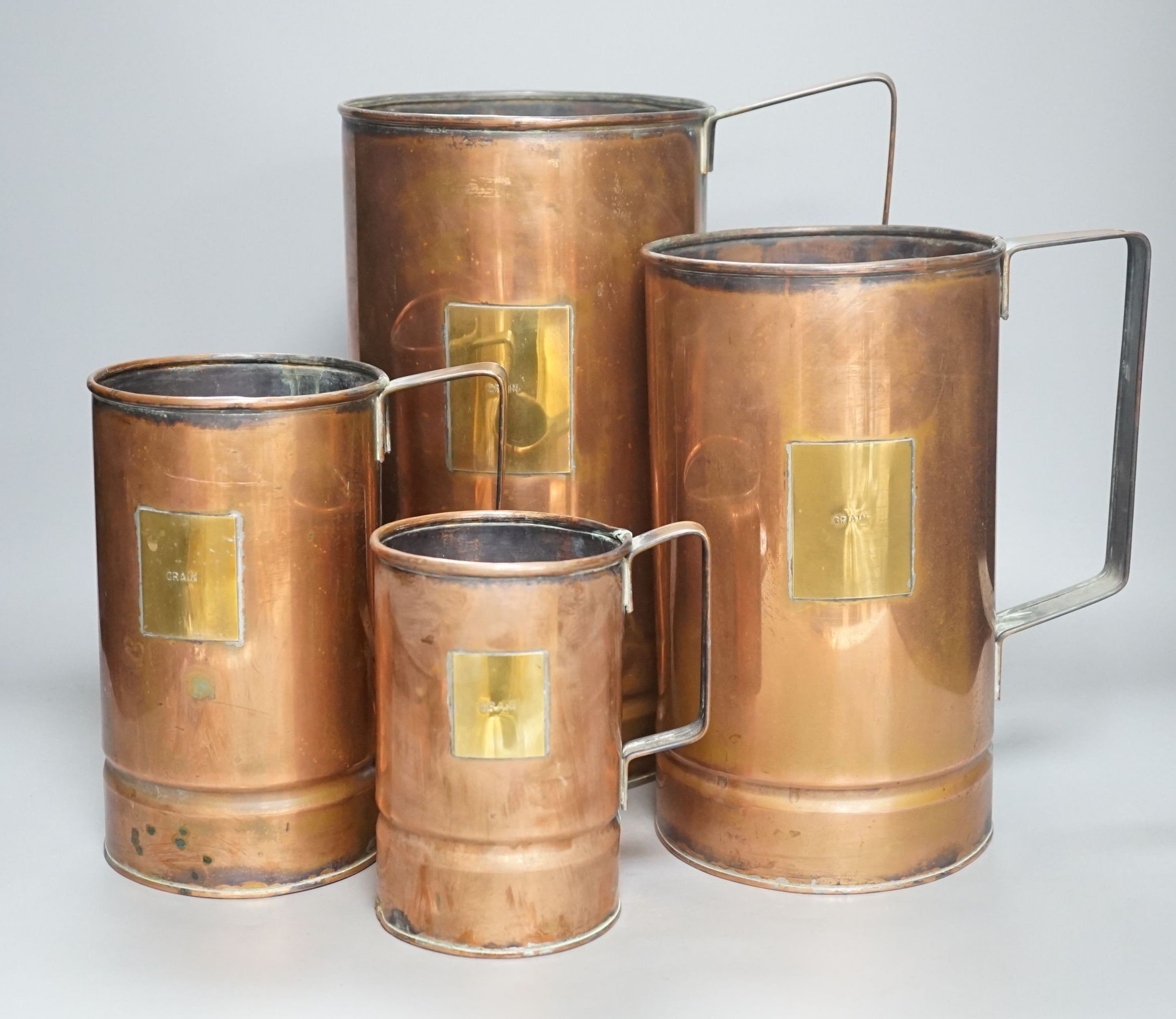 A graduated set of four copper and brass grain measures, tallest 39.5 cms high.